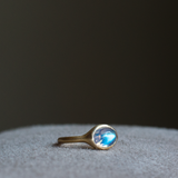 solid 14k yellow gold signet ring with bezel set bright blue sheen oval cabochon moonstone. Gold ring has brushed, matte finish