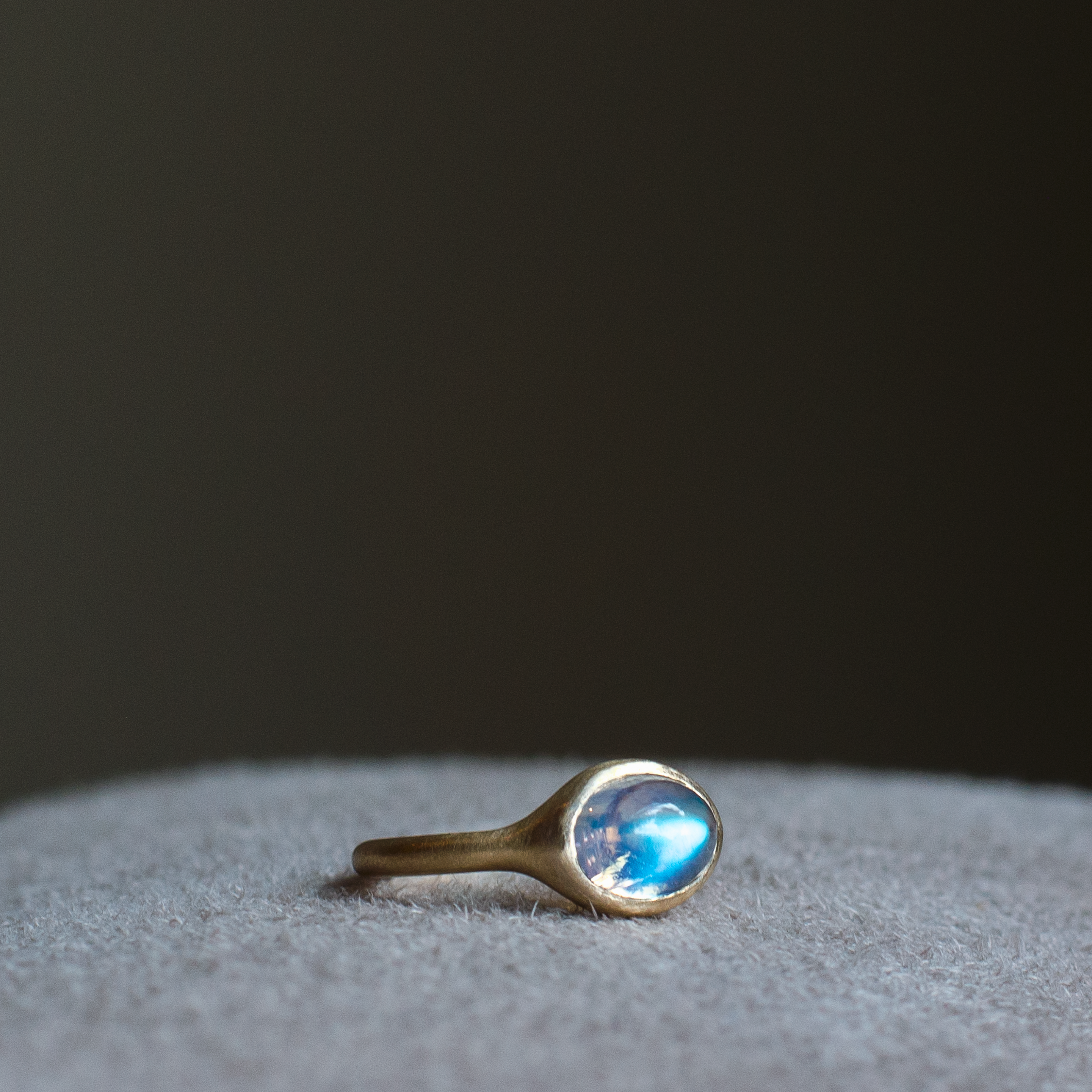 solid 14k yellow gold signet ring with bezel set bright blue sheen oval cabochon moonstone. Gold ring has brushed, matte finish
