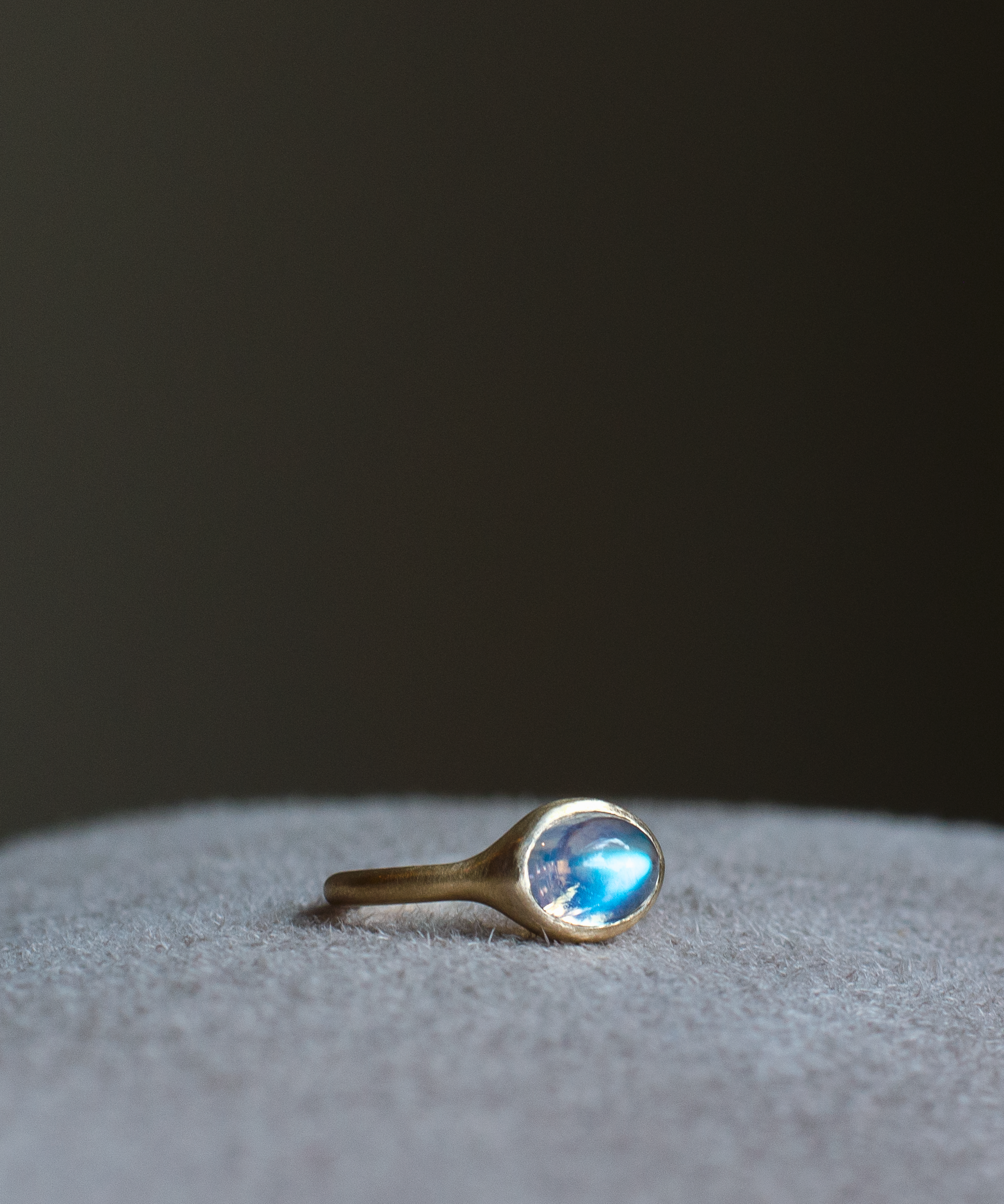 solid 14k yellow gold signet ring with bezel set bright blue sheen oval cabochon moonstone. Gold ring has brushed, matte finish