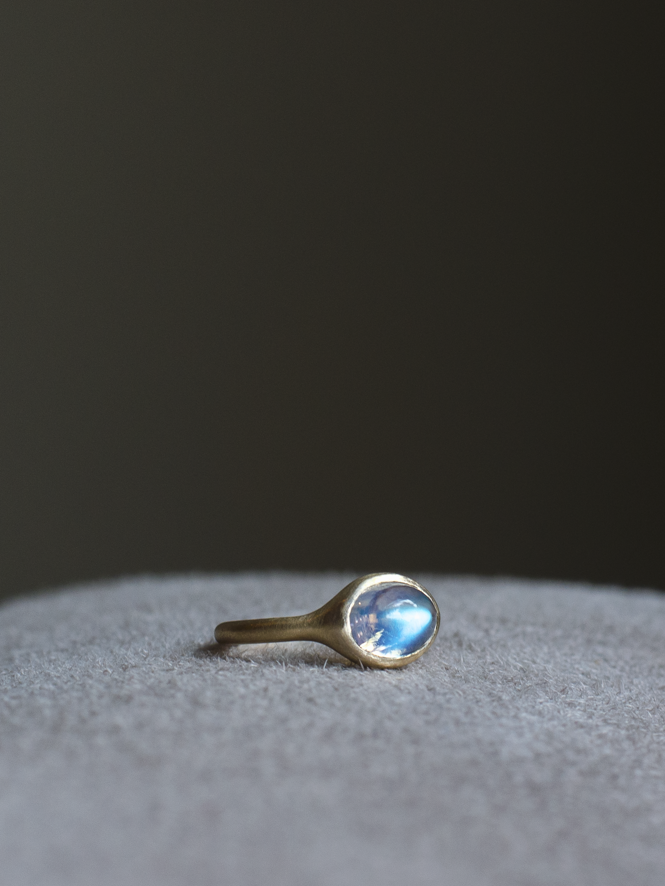 solid 14k yellow gold signet ring with bezel set bright blue sheen oval cabochon moonstone. Gold ring has brushed, matte finish