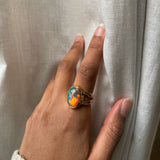 Large Black opal with rainbow and red fire bezel set in solid 14k yellow gold statement ring with split shank. Worn on model's hand