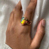 Large Black opal with rainbow and red fire bezel set statement ring with split shank worn on model's hand