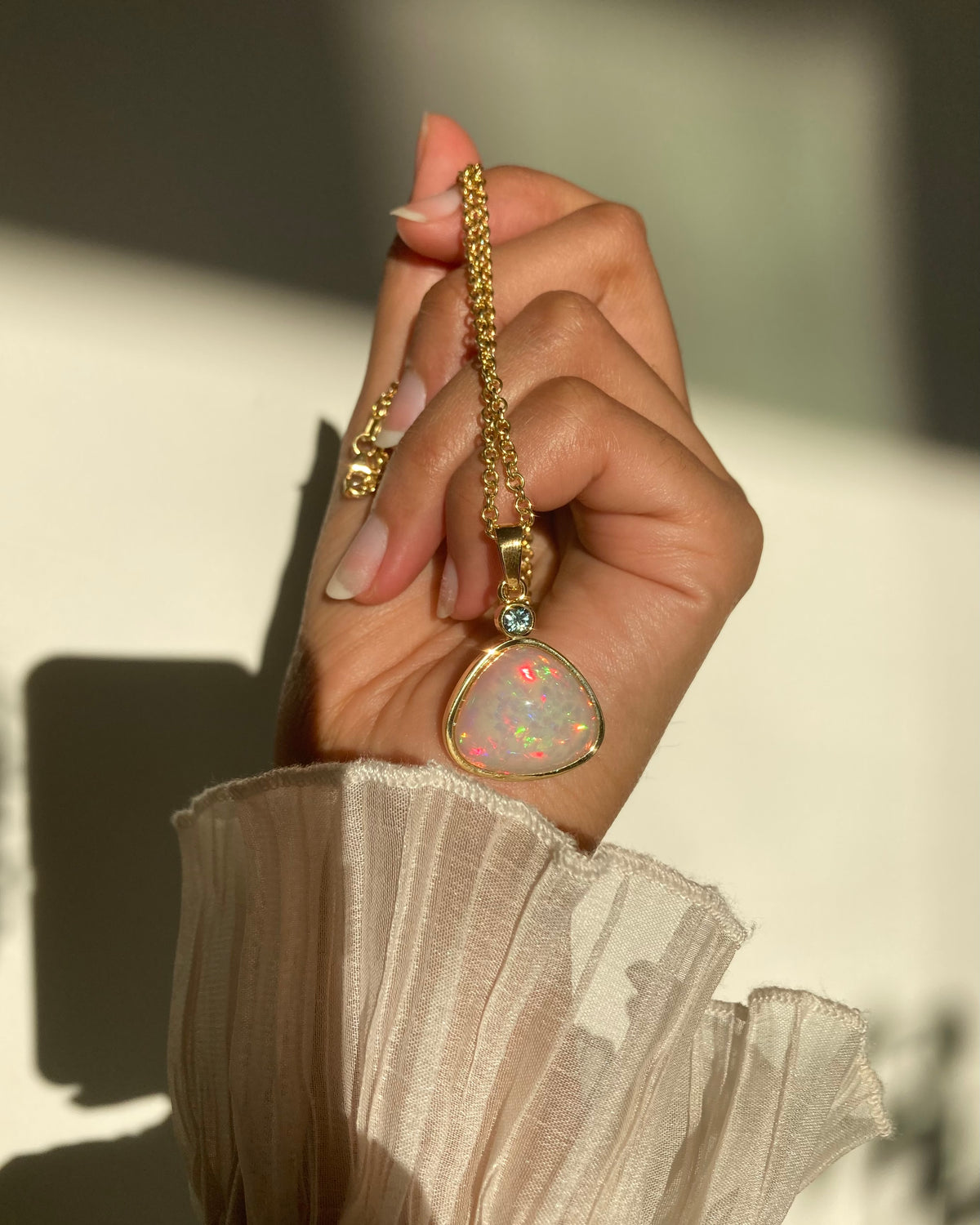 hands holding loose moonstone and pink rubellite tourmaline gemstones