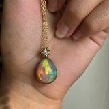 Solid gold Ethiopian Opal pendant necklace held in a hand