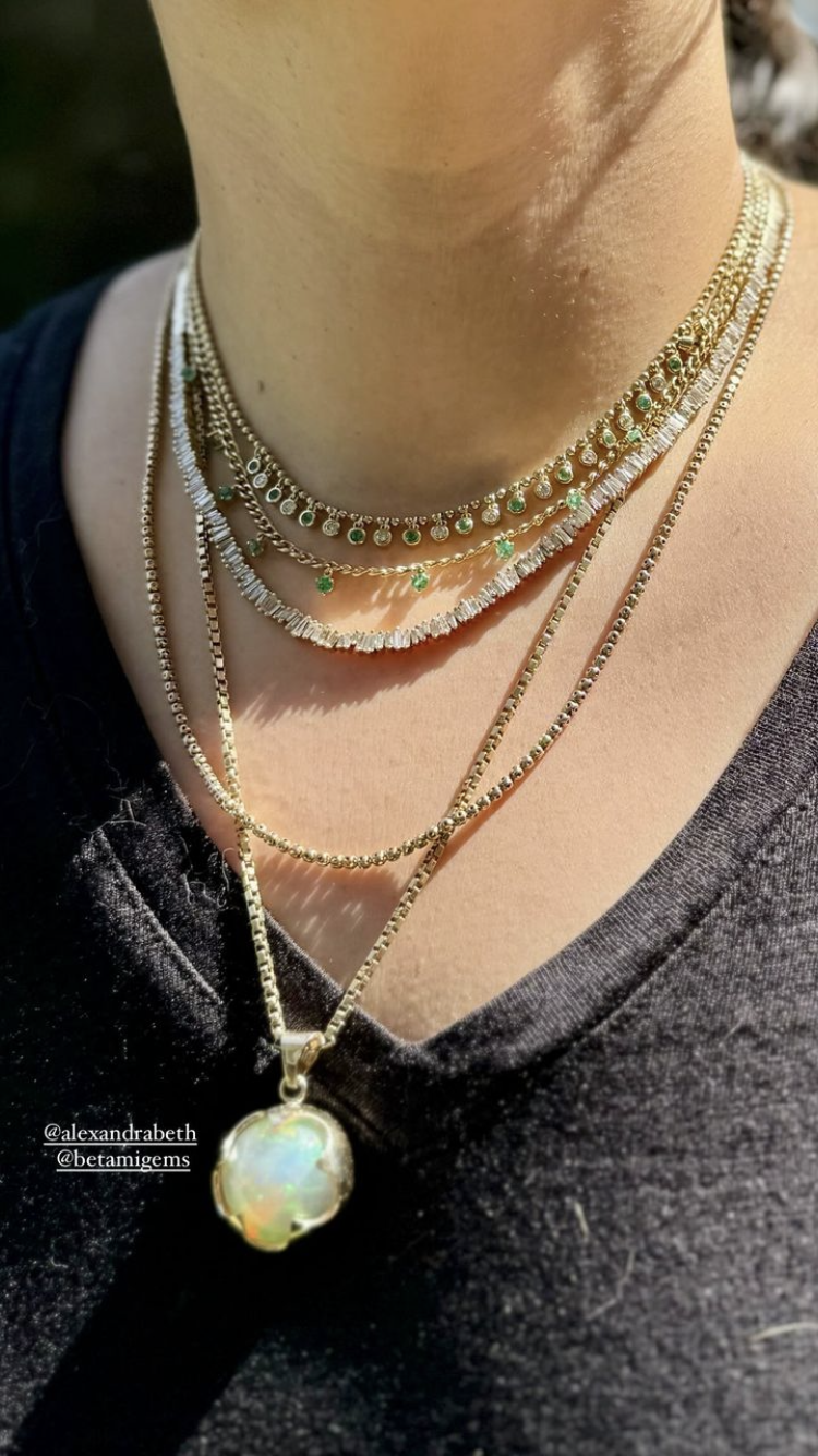 Close-up of layered gold necklaces with a prominent pendant on a dark background